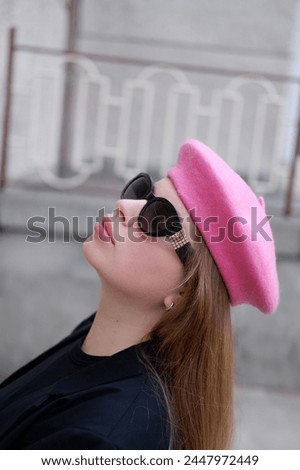 young blonde woman in a pink beret and black glasses posing for the camera. Portrait of a woman wearing a beret in Parisian style. French style. woman in sunglasses and pink beret on the street