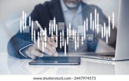 Businessman using laptop and tablet analyzing economic data and sales growth on financial charts