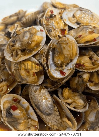 a photography of a plate of clams with sauce and a spoon.