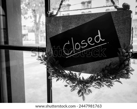 Shop closed, black notice sign with words "CLOSED !" hanging on glass door in front of the staircase in the hotel or restaurant, black and white photo style. No service, business store sign concept.