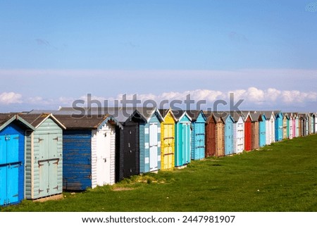 Beach huts along the Essex coast, Image shows a range of different colours and styles of beach huts on a warm spring day with slight cloud and blue sky Royalty-Free Stock Photo #2447981907