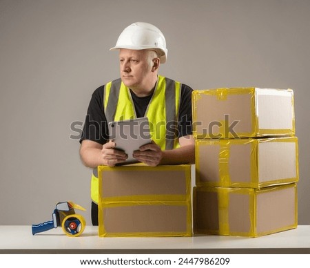 Businessman near table with boxes. Man owner fulfillment company. Guy with tablet thought about it. Businessman is engaged in fulfillment. Man prepares boxes for delivery. Fulfillment business owner