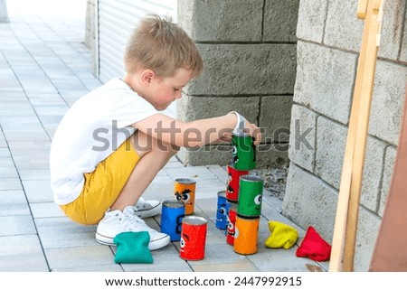 Boy plays with cubes on a summer playground. Stocks and color tins of the traditional game Kubb. High quality photo