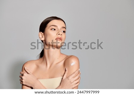A young woman with brunette hair confidently poses with her arms crossed in a stylish studio portrait.