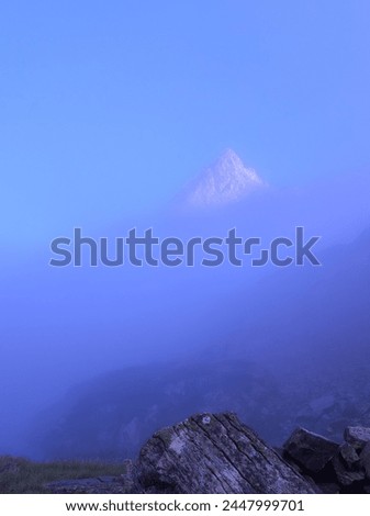 High snow-covered mountain visible through a light mist in front of a magnificent blue sky Royalty-Free Stock Photo #2447999701