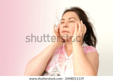 diseased mature woman experiences severe headache, holding head, Hot flashes during menopause, Decreased memory and concentration, feeling nervous, Feeling tired, exhausted, menopause, midlife crisis Royalty-Free Stock Photo #2448011119