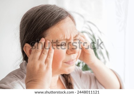 diseased mature woman experiences severe headache, holding head, Hot flashes during menopause, Decreased memory and concentration, feeling nervous, Feeling tired, exhausted, menopause, midlife crisis Royalty-Free Stock Photo #2448011121