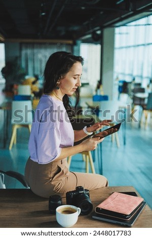 Photographer female student with coffee using laptop working with photography in coworking space, young freelancer working remotely with web design