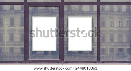 Two blank advertising spaces framed borders with white space for mockup in urban setting. Reflection of classic architecture in window panes hints at bustling city life.