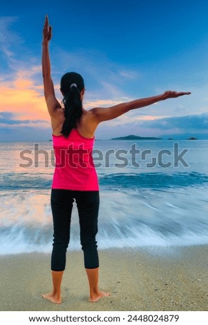 A lone woman standing on a beach facing the sea