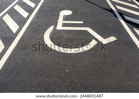 Disabled parking sign painted on ground. Symbol indicating reserved parking space for individuals with disabilities. Concept of accessibility and inclusion.