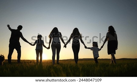 big family. silhouette of a large family walking in the park at sunset sunbeams holding hands. happy family child dream concept. friendly family silhouette at sunset in nature rest in park walking