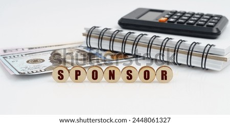Business and finance concept. On a high surface lie a notepad, a calculator, dollars and wooden circles with the inscription - SPONSOR