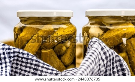 Glass jars with pickled red bell peppers and pickled cucumbers (pickles) isolated. Jars with variety of pickled vegetables. Preserved food concept in a rustic composition. Royalty-Free Stock Photo #2448076705
