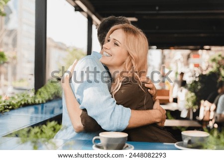 Cheerful caucasian romantic couple married spouses boyfriend and girlfriend friends hugging embracing while on a date in cafe restaurant, drinking coffee. Royalty-Free Stock Photo #2448082293