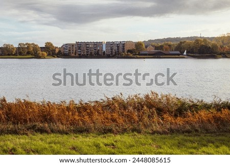 Autumn Lakeside view with residential area on opposite bank at Caldecotte lake Royalty-Free Stock Photo #2448085615