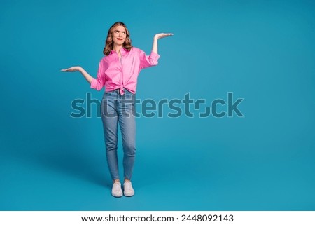 Full body photo of pretty young girl compare skeptical empty space wear trendy pink outfit hairdo isolated on blue color background