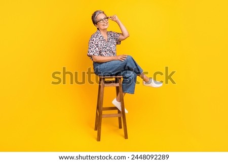 Full size photo of pretty retired female sit chair touch specs dressed stylish leopard print outfit isolated on yellow color background