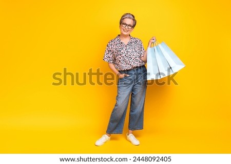 Full length photo of lovely senior lady hold shopping bags dressed stylish leopard print garment isolated on yellow color background