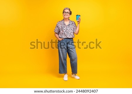 Full body photo of attractive pensioner woman coffee empty space dressed stylish leopard print clothes isolated on yellow color background