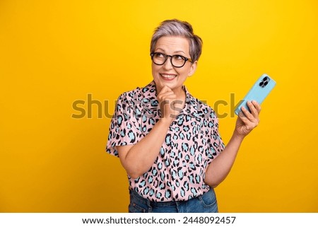 Photo portrait of pretty retired female device look empty space dressed stylish leopard print outfit isolated on yellow color background
