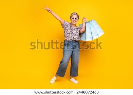 Full length photo of lovely senior lady shopping bags show v-sign dressed stylish leopard print garment isolated on yellow color background