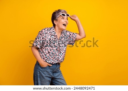 Photo of lovely senior lady take off sunglass shock look empty space wear trendy leopard print garment isolated on yellow color background