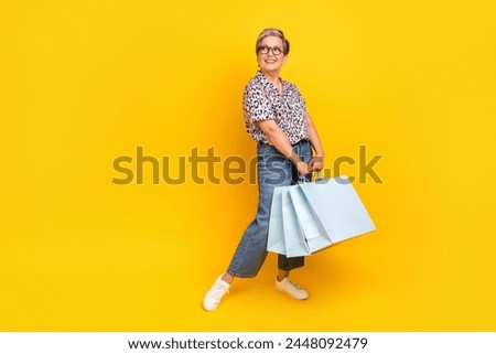 Full length photo of lovely senior lady shopping look empty space wear trendy leopard print garment isolated on yellow color background