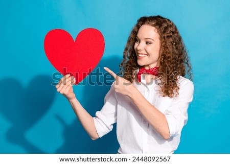 Photo portrait of pretty young woman hold point big red heart postcard dressed stylish white clothes isolated on blue color background