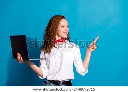 Photo portrait of pretty young woman point look empty space hold netbook dressed stylish white clothes isolated on blue color background