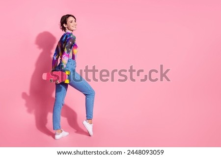 Full size rear photo of nice young woman hold skate look empty space wear pullover isolated on pink color background