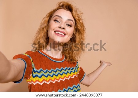 Portrait of nice girl with wavy hairdo wear ornament t-shirt making selfie palm presenting empty space isolated on beige color background