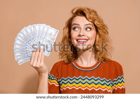 Photo portrait of lovely young lady hold look money dollars dressed stylish striped garment isolated on beige color background