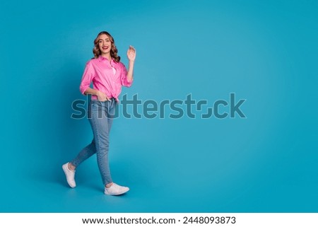 Full body photo of pretty young girl wave hand walking wear trendy pink outfit hairdo isolated on blue color background
