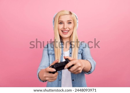 Photo of young excited girl play game wireless earphones free-time isolated over pink color background