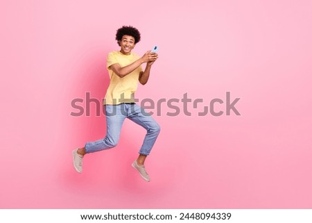 Full size photo of active sporty person hold smart phone jumping empty space isolated on pink color background