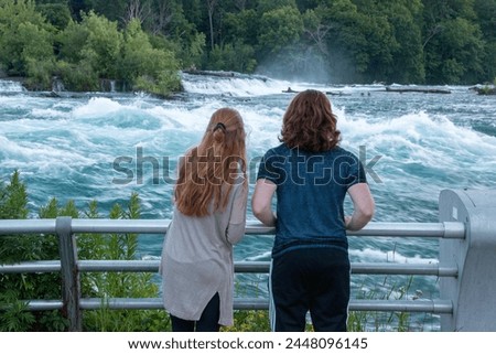 Young man and woman looking at the Niagara River Royalty-Free Stock Photo #2448096145