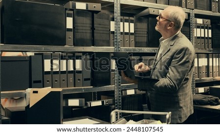 Private investigator searching for files based on case names in archive, looking for legal documents and classified information on laptop. Agent working on criminology in incident room. Camera B. Royalty-Free Stock Photo #2448107545