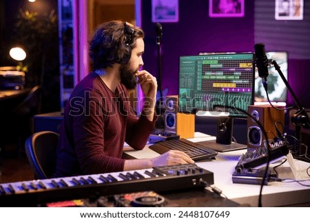 Artist composer producing music using stereo panel controls and electronic gear, twisting pre amp knobs for mixing and mastering techniques. Audio engineer adjusting songs volume.