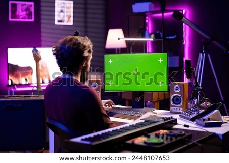 Sound engineer learning to mix and master audio recordings by watching post production tutorials online on pc with greenscreen. Artist editing tunes and adjusting volume levels in home studio.