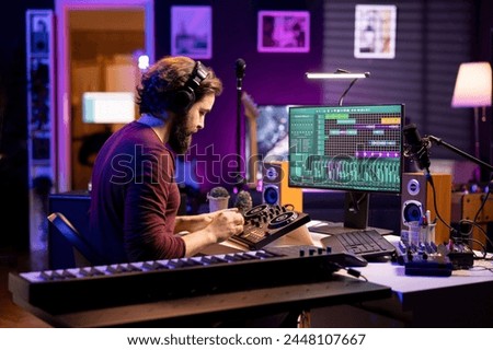 Young artist mixing and mastering tunes on professional console, adding sound effects in editing session before launching new music. Audio producer songwriter creating tunes in home studio.