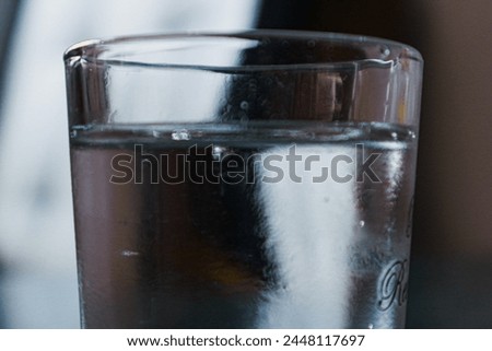 detail close up shot of clear cold mineral water in a clear drinking glass with background blur
