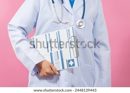 Holding clipboard medical form, Close up female medical doctor isolated on pink background.