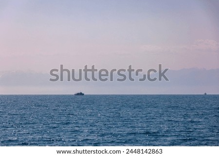 Two boats with Kyrgyzstan flag on Issyk-Kul lake at summer day with mountains on horizon.