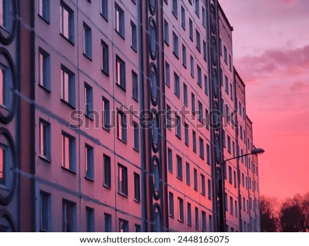 Multi-storey, multi-apartment residential building. Soviet period built in the seventies - eighties of the twentieth century. Red Sunset, evening time. Royalty-Free Stock Photo #2448165075