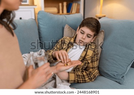 Sick child taking medicine tablet, flu treatment and cold cure for illness, sickness and virus symptoms. Mom caring for health of little son, kid and boy to rest, recover and get better in bed at home
