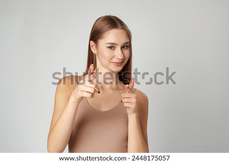 Young Woman Pointing Towards Camera With a Playful Expression in a Studio