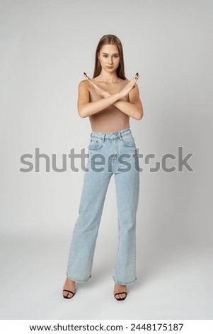 Young serious woman crossed hands show stop symbol on gray background