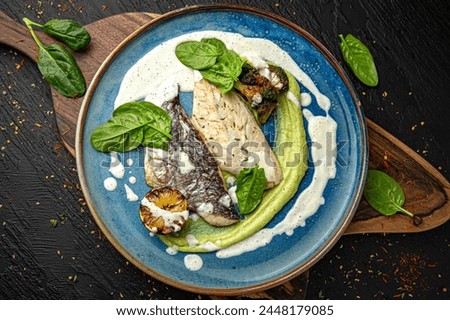Grilled dorado fillet with zucchini slice and lime. Menu for a pub on a dark background. Colorful juicy food photography.