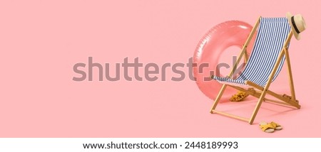 Deck chair and beach accessories on pink background with space for text